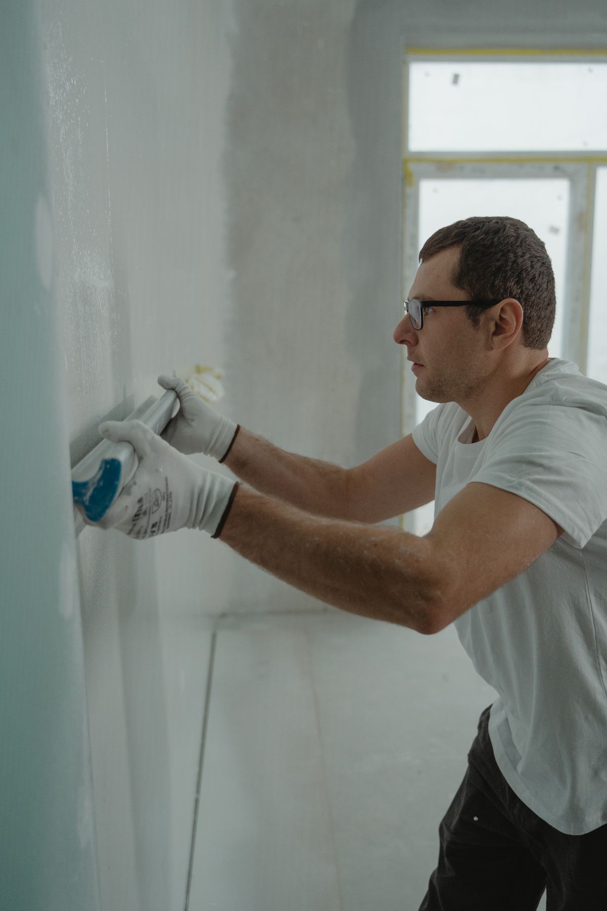 Contractor applying joint compound to drywall with a smoothing tool during a repair